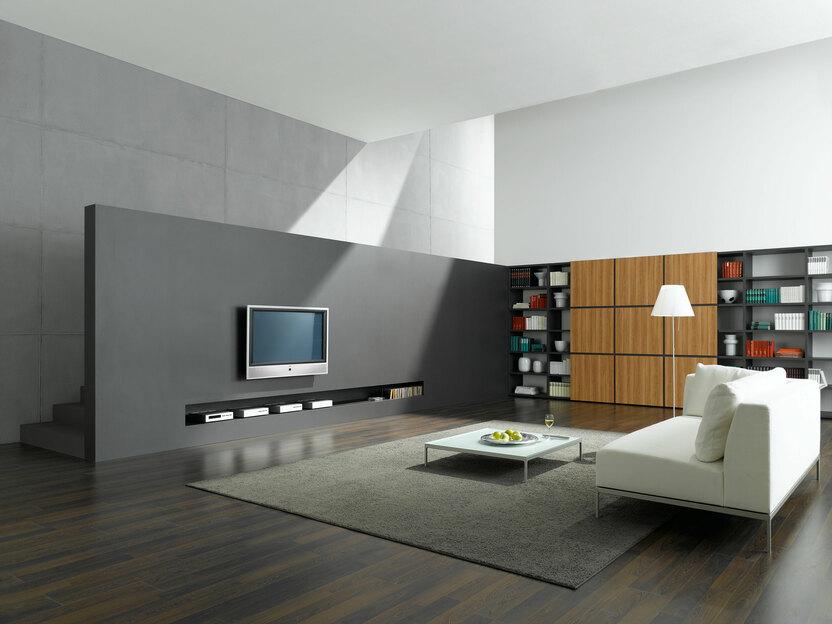 Wohnraumimpression mit Fernsehwand zur Treppe Offene Wohnraumimpression mit grauer TV-Trennwand zur Treppe und Einbauregal aus Holz und weißem Sofa